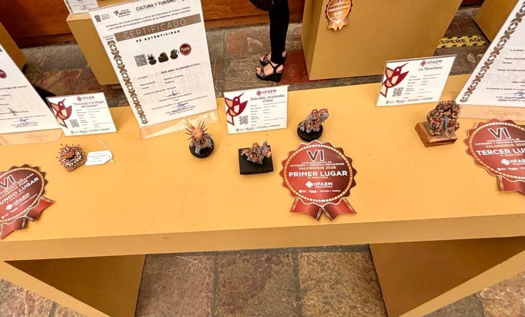 Miniaturas de barro premiadas en el concurso del IIFAEM, de entre cuatro y seis centímetros, exhibidas junto a sus certificados de autenticidad y escarapelas de primer, segundo y tercer lugar