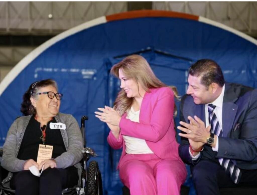 Beneficiaria en silla de ruedas es aplaudida por la presidenta del DIF Puebla y el gobernador Alejandro Armenta Mier durante la inauguración del hospital itinerante